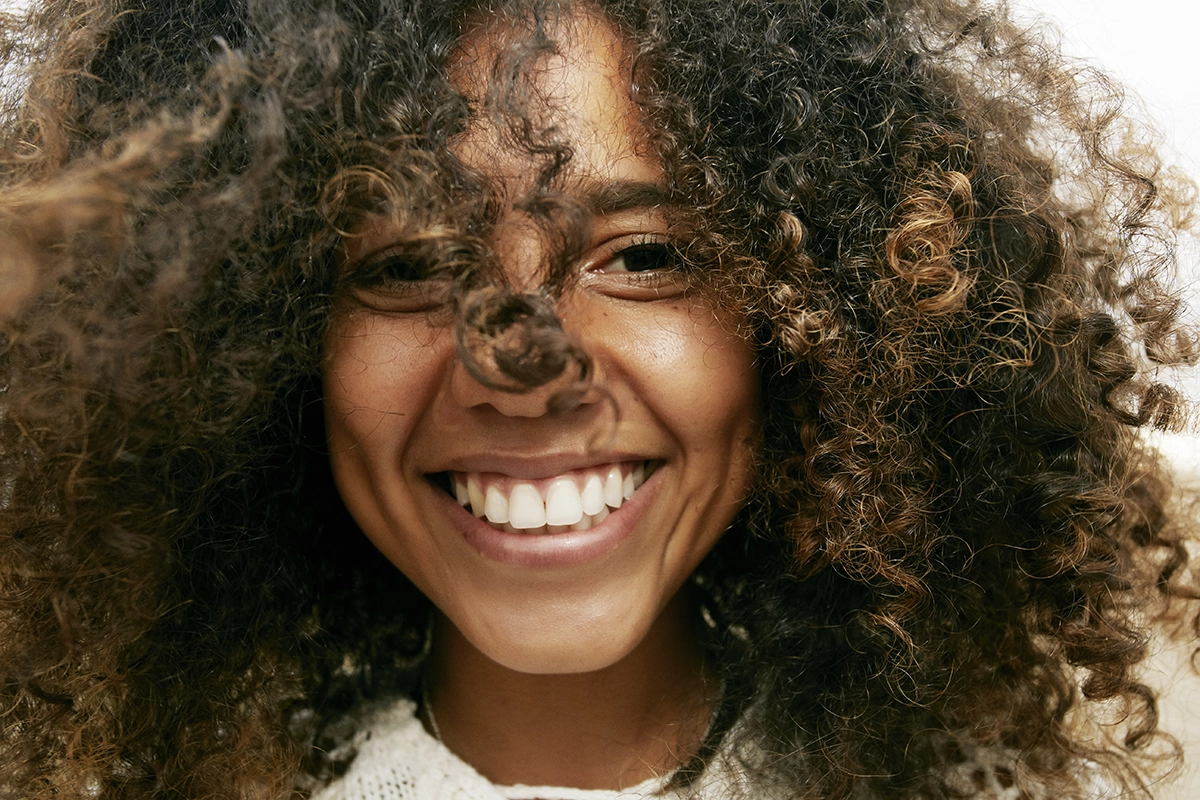 portrait-of-smiling-young-woman-with-brown-curly-hair